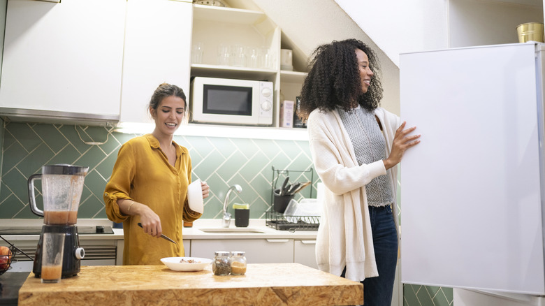 Women talking and using a hand blender in an open-concept kitchen