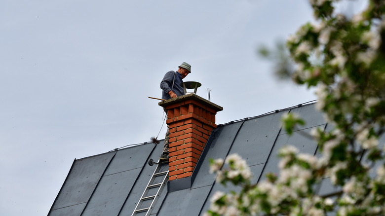 chimney sweep on a ladder to repair chimney