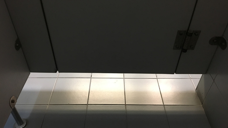A restroom showing a noticeable gap between the bottom of the door and the floor