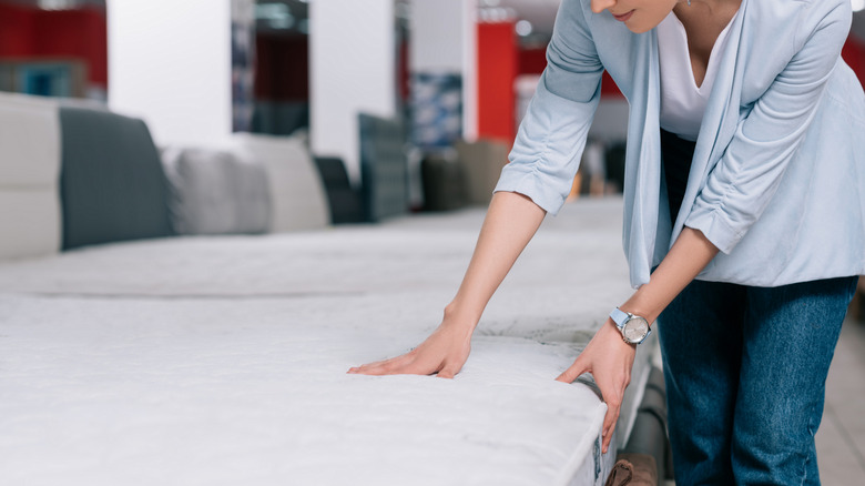 Woman touching a mattress in a store