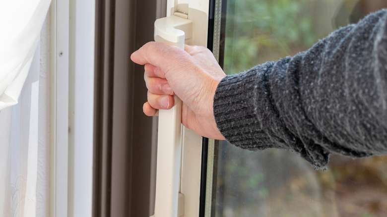 A person's hand is trying to open a stuck sliding glass door