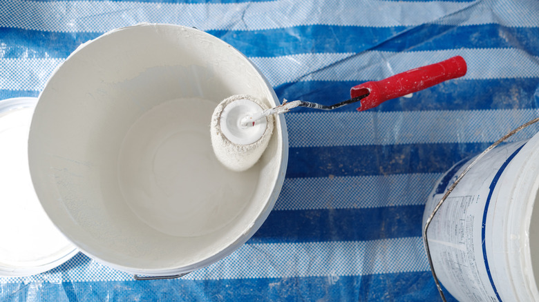 A paint roller in a bucket of white paint