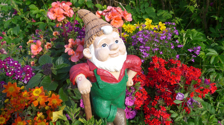 Garden gnome sits among flowers