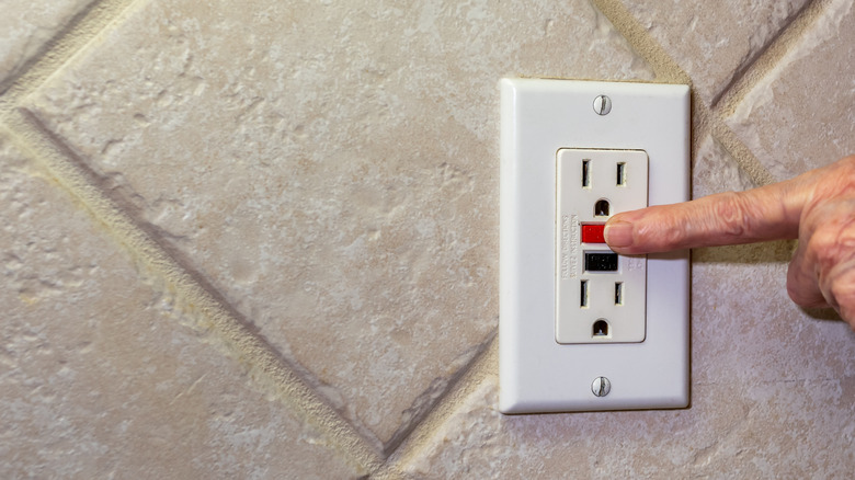 Person pressing GFCI reset button