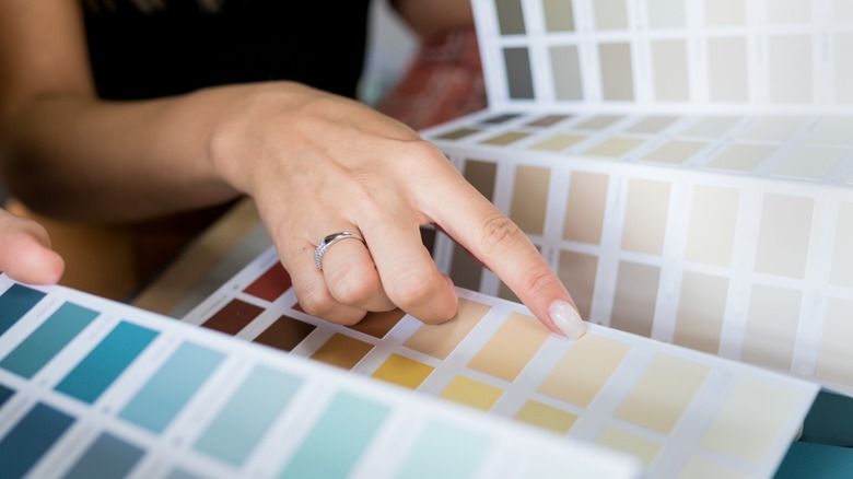 A hand selecting paint can colors from a sample book