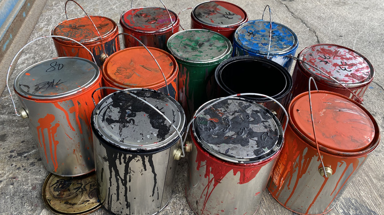 Used cans of paint sitting on a garage floor