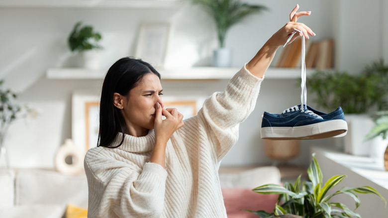 Woman holding up stinky shoes