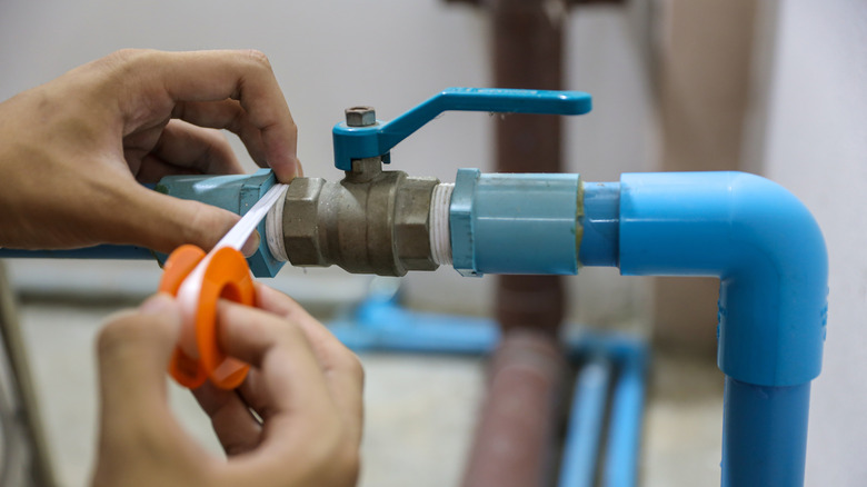 Person sealing a pipe with white tape