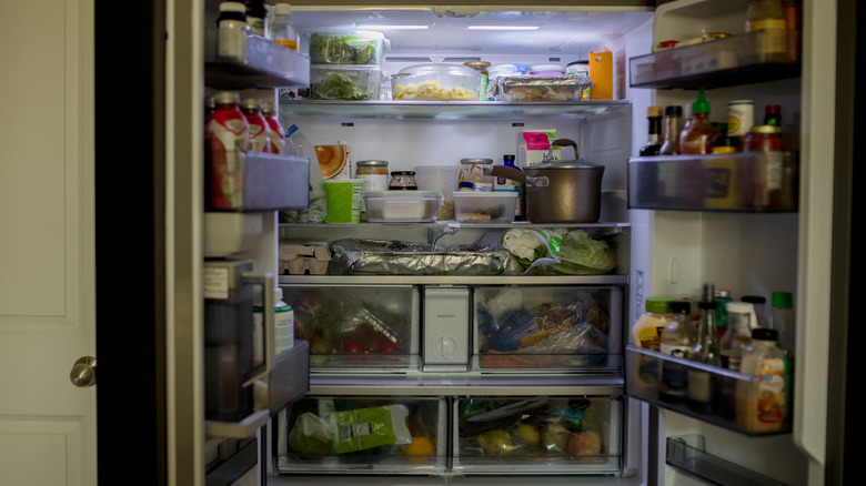 An overstuffed fridge with brimming side shelves