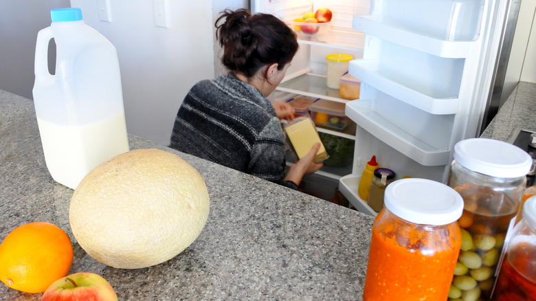 Woman going through the food items in a fridge