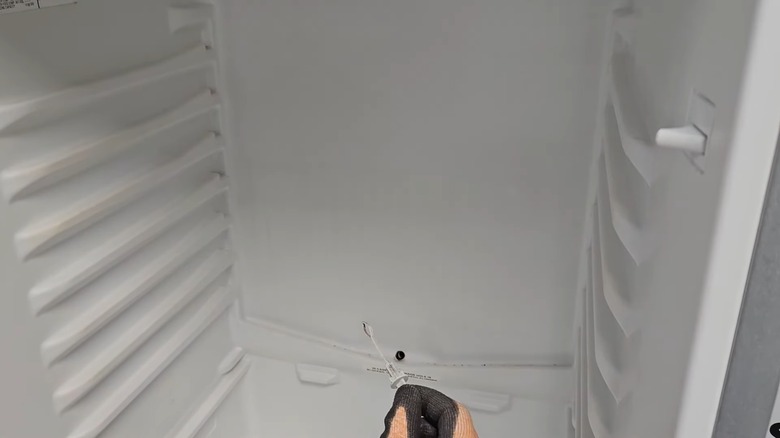 Hand holding the stopper of a fridge drain hole