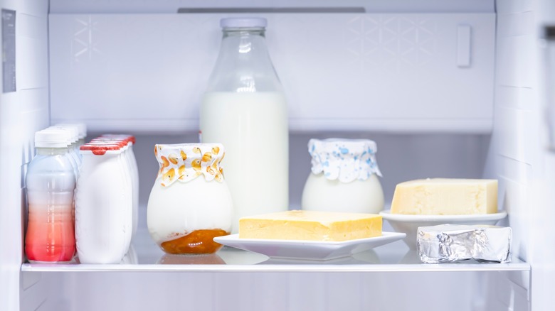 Food items in covered and uncovered containers on a fridge shelf