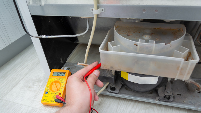 Professional checking a fridge with a digital multimeter