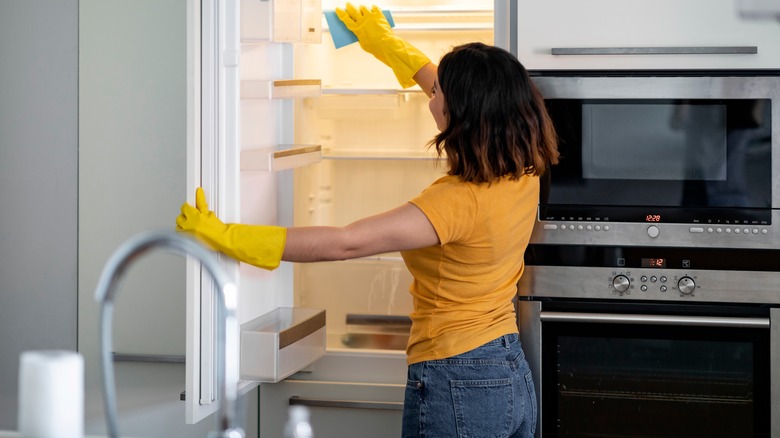 Woman wiping an empty fridge