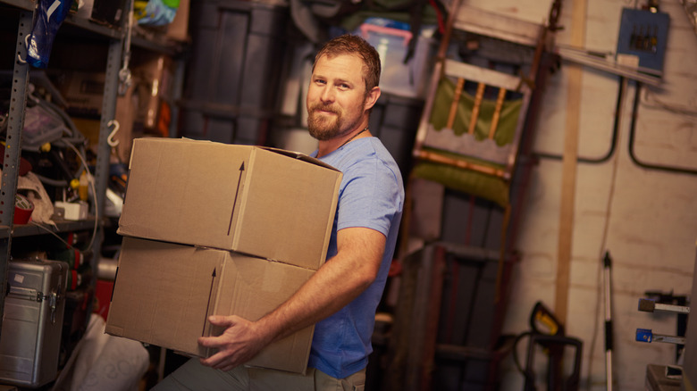 person carrying cardboard boxes in garage