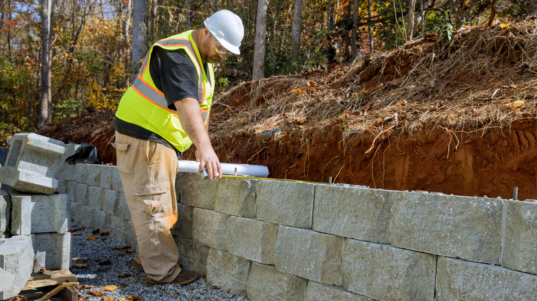 A worker building a retaining wall with concrete blocks
