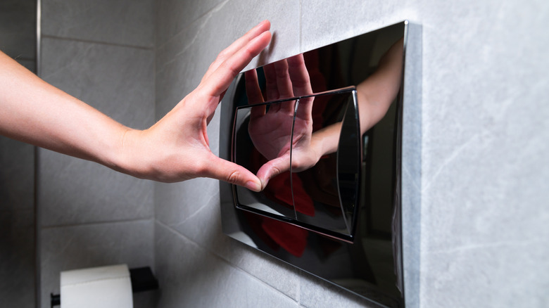 Closeup of person's hand flushing a dual-flush toilet