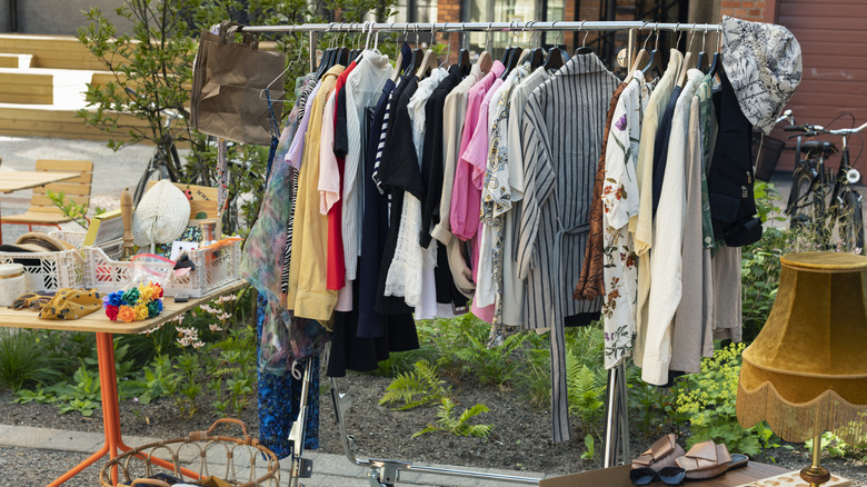 Estate sale with clothing rack and tables of items.