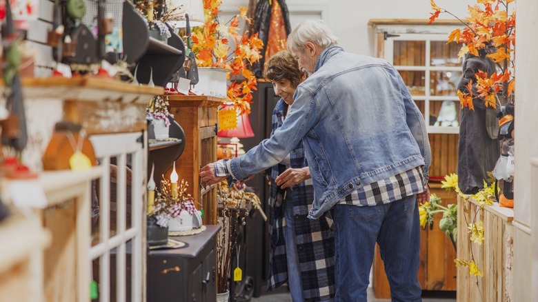 couple looking at vintage furniture in thrift store with fall decorations