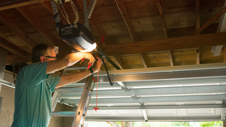 A man in a green shirt working on a garage door.