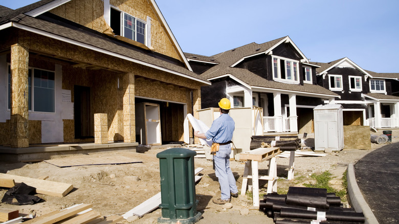 A construction worker looks at several subdivision homes that are under construction