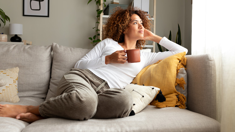 Woman relaxing on sofa holding a mug of coffee
