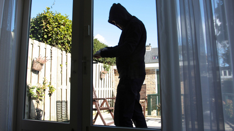 Burglar wearing black clothes and a hoodie to break into a house