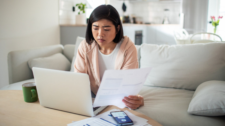 A person studying a bill with a concerned look
