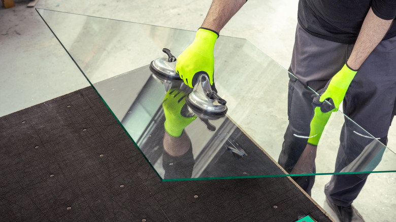 A professional lifting a glass panel using specialized suction cups