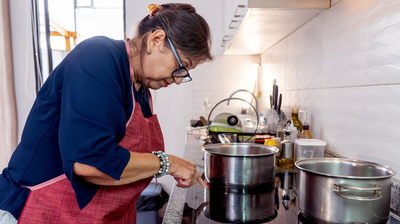 Elderly woman cooking with an induction stove in a modern kitchen