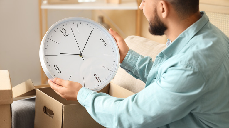 man unpacking large analog clock