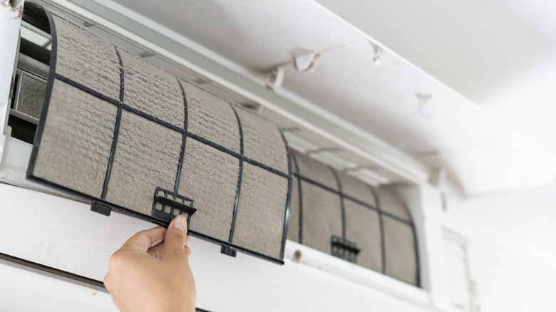 Hand removing a dusty air filter