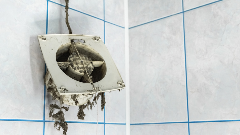 Dusty exhaust fan against tiled wall