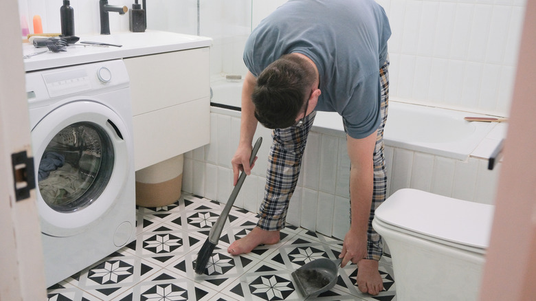 Man sweeping dust from bathroom floor