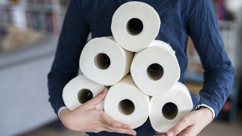 Person holding several rolls of toilet paper
