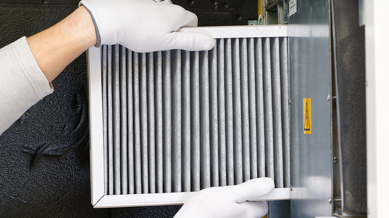 Person wearing gloves changing an HVAC filter