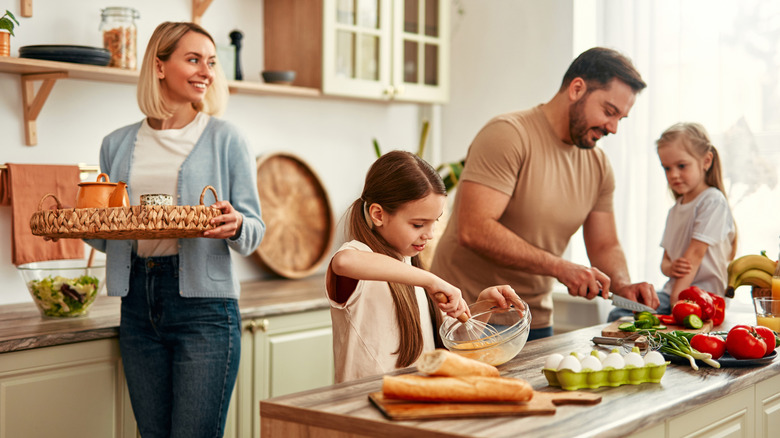 A happy family is cooking together in a bright kitchen.