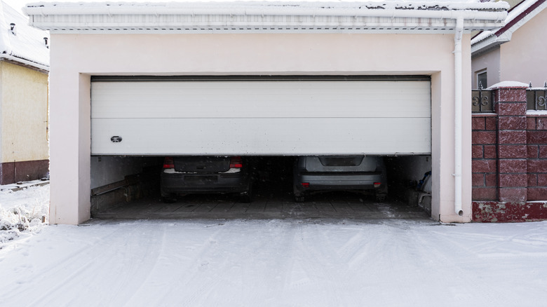 Exterior of a garage attached to a house. garage with two cars inside in winter