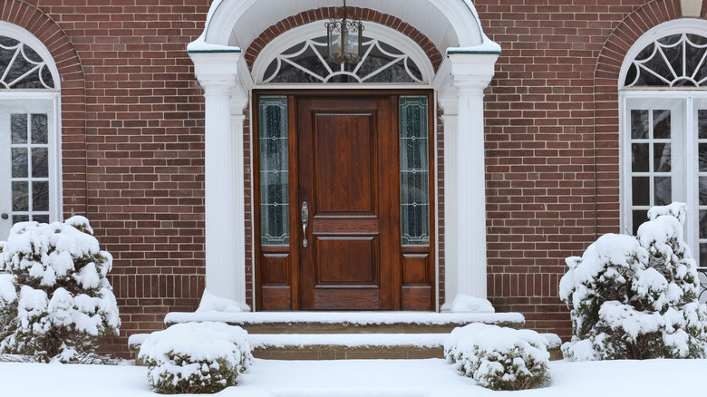 door of brick home with snowy lawn 