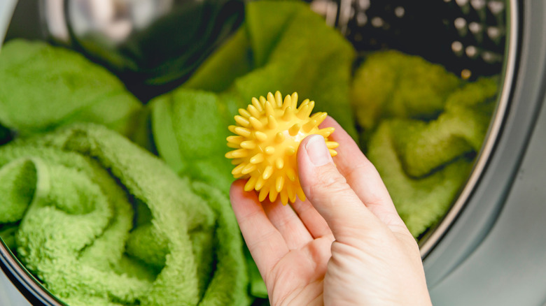 A person holds up a plastic dryer ball in front of the dryer