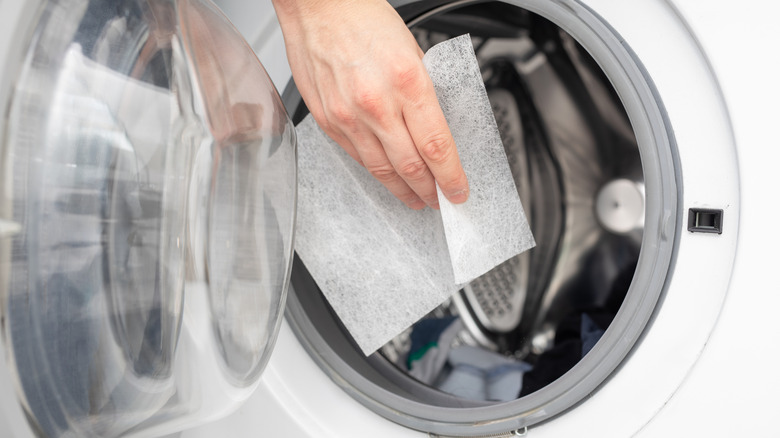 Person putting a dryer sheet in the dryer