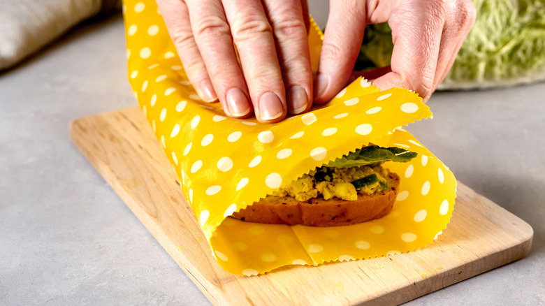 hand holding sandwich wrapped in beeswax wrapping
