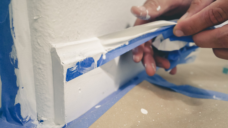 person peeling tape off baseboard