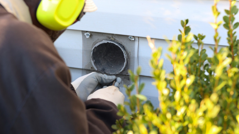 A man installing mesh over an external dryer vent