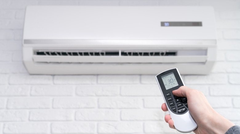 Air conditioner temperature adjustment with remote controller in room at home.