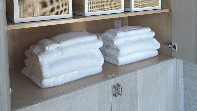 A set of bathroom towels are folded and organized in a linen closet.