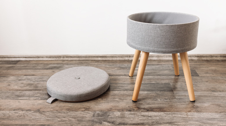 A small, modern gray storage ottoman with the lid removed