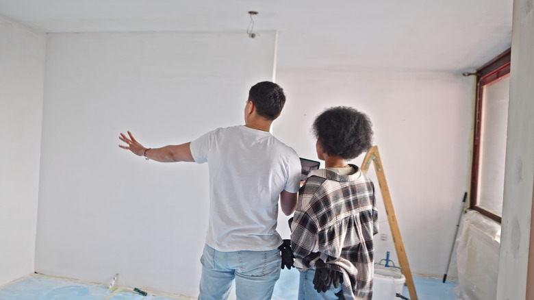 Two people stand in a freshly painted room while discussing the finish.