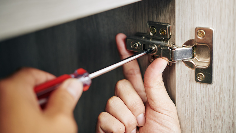 Person turning screw in hinge