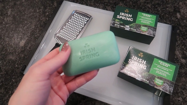 Person holding Irish Spring bar soap above counter with grater and cutting board